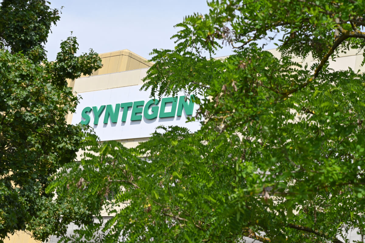 Syntegon-Gebäude umgeben von grünen Bäumen, das Engagement für Nachhaltigkeit symbolisiert.