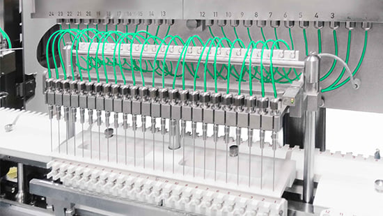 Time-pressure filling system with multiple nozzles and green tubing, integrated into a pharmaceutical filling machine for high-speed, precise dosing in aseptic environments.