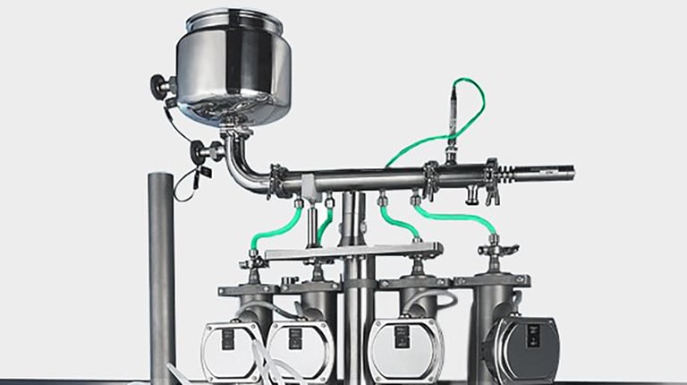 Mass flow filling system with precision sensors and stainless steel piping, integrated into a pharmaceutical filling machine for accurate, real-time liquid dosing.