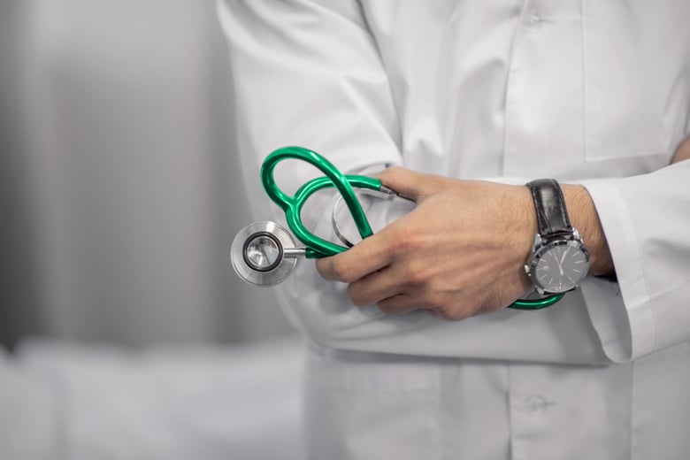 Doctor holding a stethoscope in front of white coat.